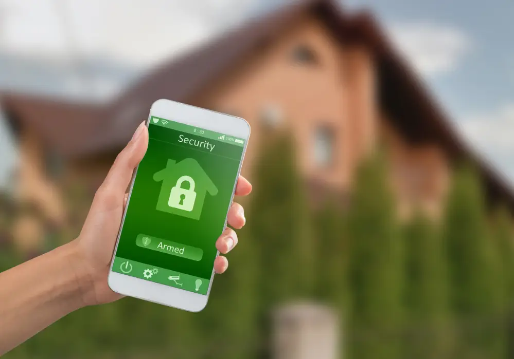 woman holding a mobile phone displaying that her home is locked with her smart security system